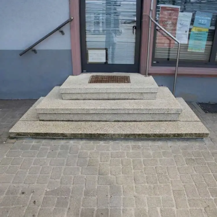 Vorher-Nachher-Vergleich einer Treppensanierung: Dreistufige Treppe im Eingang eines Ladengeschäfts vor den Arbeiten.